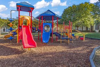 A playground with a red slide and a blue slide